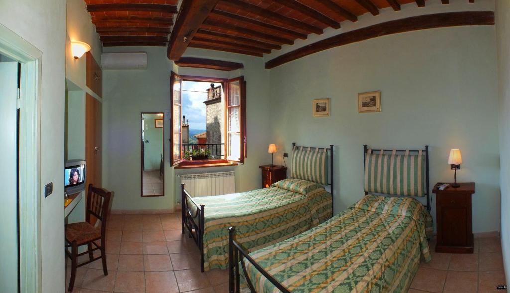 Civitella MarittimaにあるLocanda nel Casseroのベッド2台と窓が備わるホテルルームです。