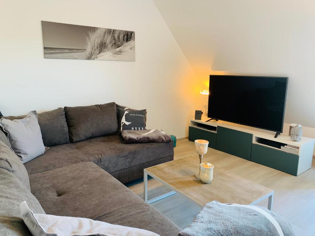 a living room with a couch and a flat screen tv at Ferienwohnung Syltliebe in Wenningstedt