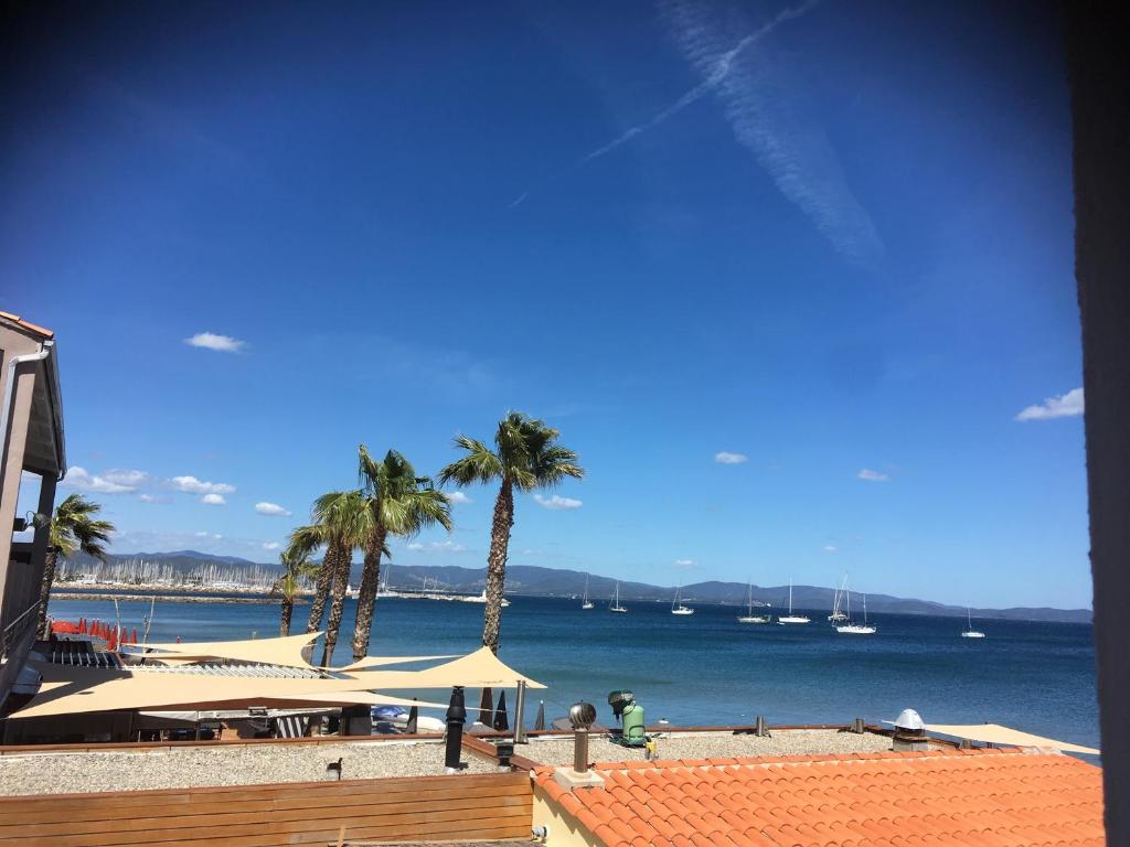 - une vue sur la plage bordée de palmiers et l'océan dans l'établissement Hôtel Lido Beach, à Hyères