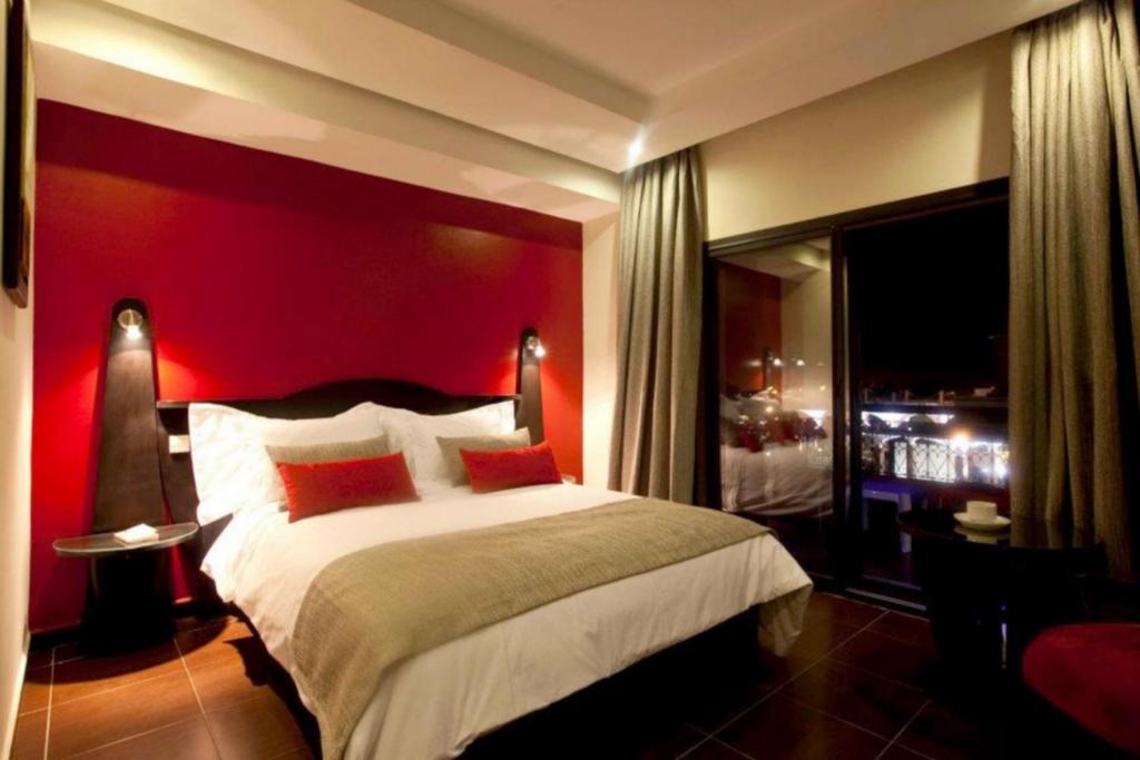 a bedroom with a large bed with a red wall at Red Hotel Marrakech in Marrakesh