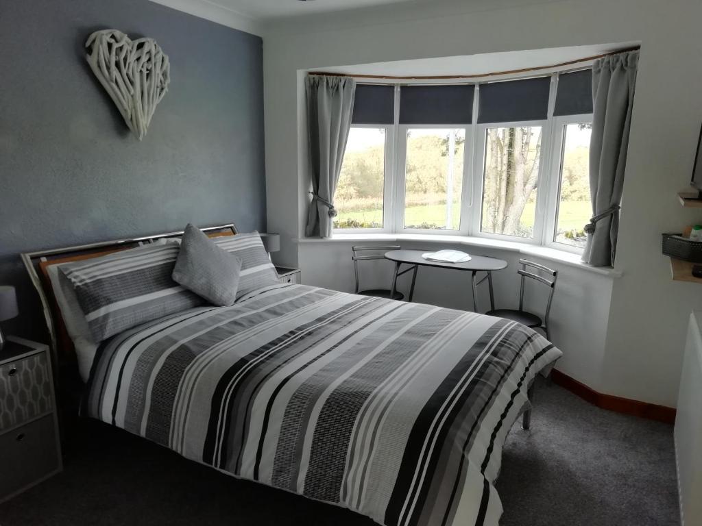 a bedroom with a bed and a window and a table at Rockville Amlwch LL68 0TE, UK Apartment in Llanfflewyn