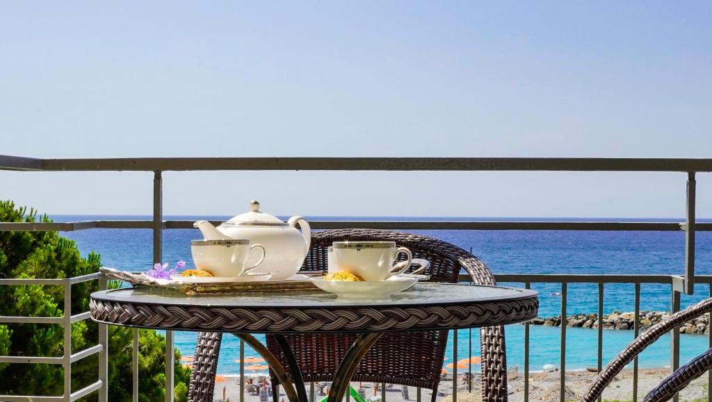 a table with a tea set on a balcony overlooking the ocean at Sole Mare in Ventimiglia