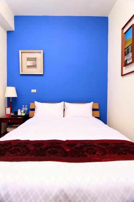 a blue bedroom with a white bed and a blue wall at Plentiful-Inn Kenting in Hengchun South Gate
