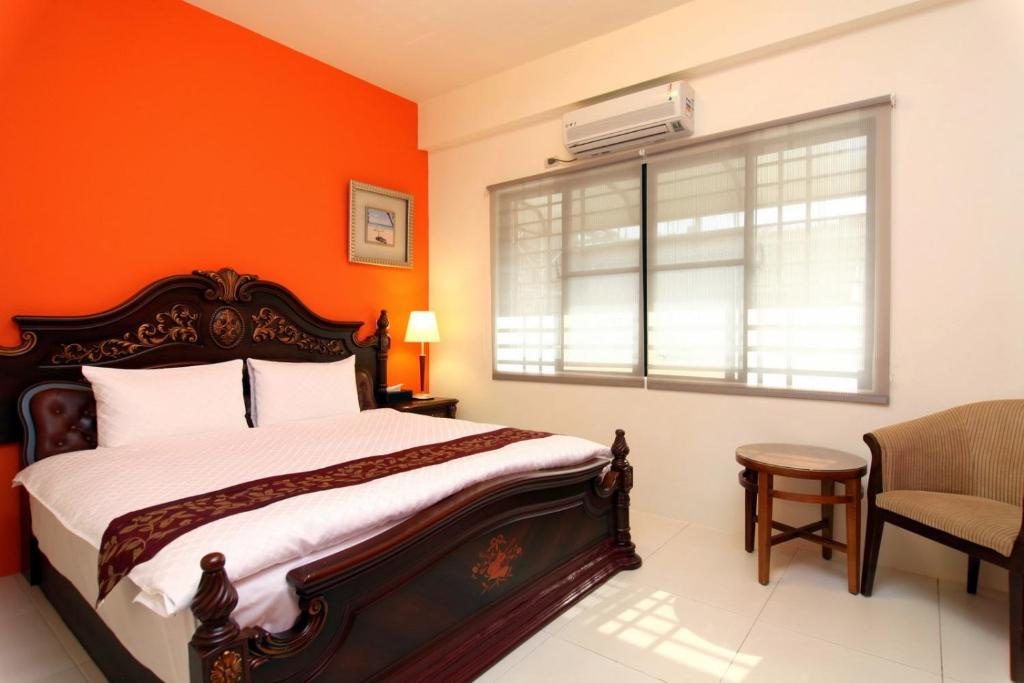 a bedroom with orange walls and a bed and a window at Plentiful-Inn Kenting in Hengchun South Gate