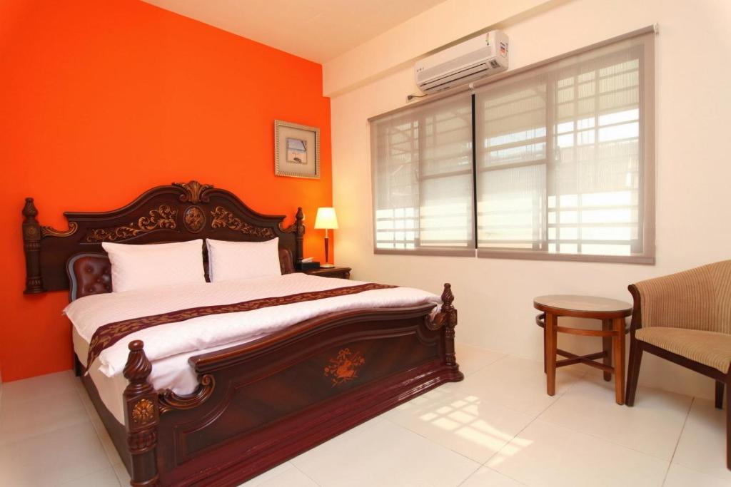 an orange bedroom with a bed and a window at Plentiful-Inn Kenting in Hengchun South Gate