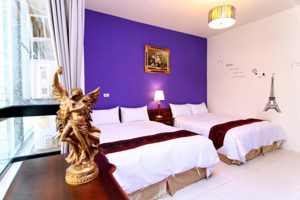 two beds in a room with a purple wall at Plentiful-Inn Kenting in Hengchun South Gate