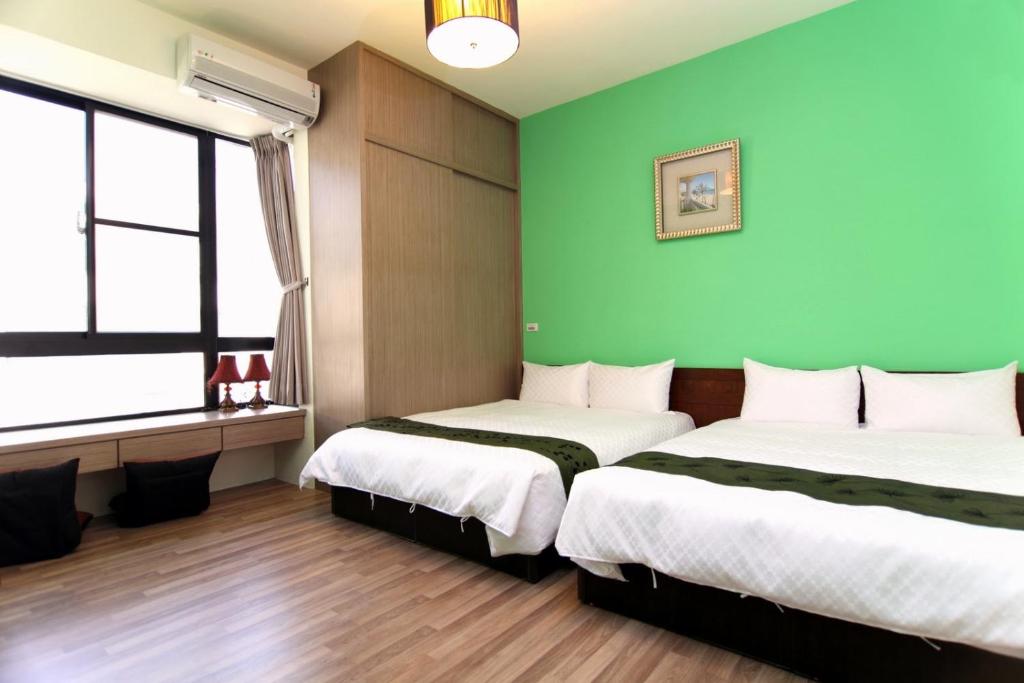 two beds in a room with green walls at Plentiful-Inn Kenting in Hengchun South Gate