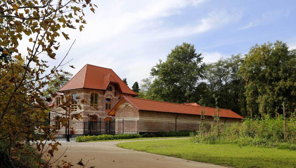 un grand bâtiment en briques avec un toit rouge dans l'établissement B&B Hippo-Droom, à Hoeilaart