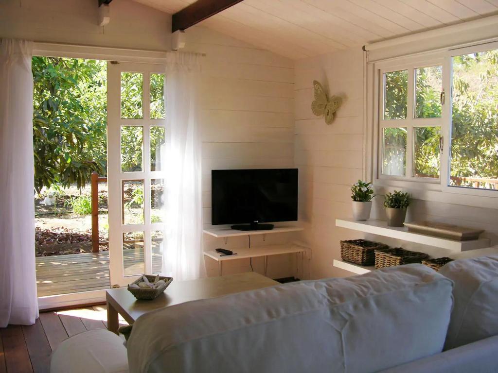 een woonkamer met een bank en een flatscreen-tv bij Cottage Bougainville in La Orotava