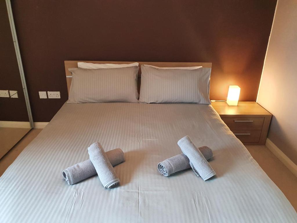a bed with three pillows on top of it at Library Square Penthouse in Belfast