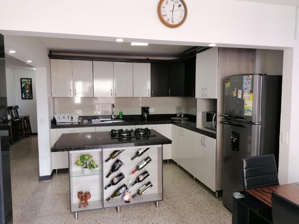 a kitchen with white cabinets and a black refrigerator at Casa Melodía Guatapé - Excelente Ubicación - Calle del Comercio in Guatapé