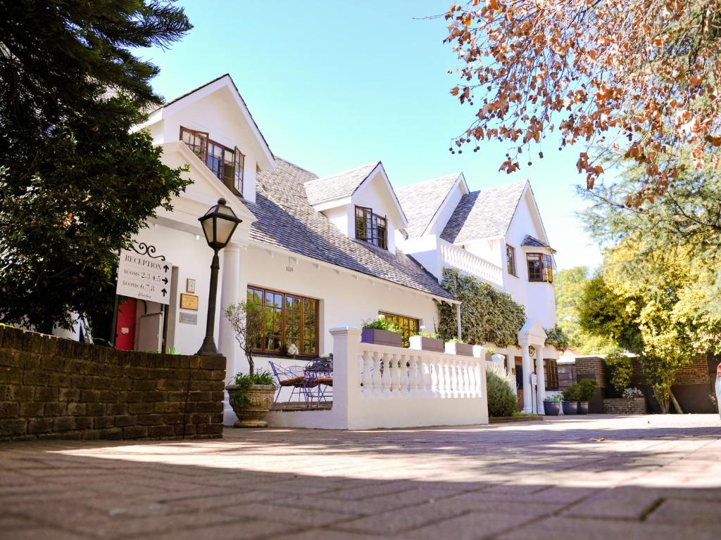 una casa blanca con una valla delante en 5th Avenue Gooseberry Guest House en Johannesburgo