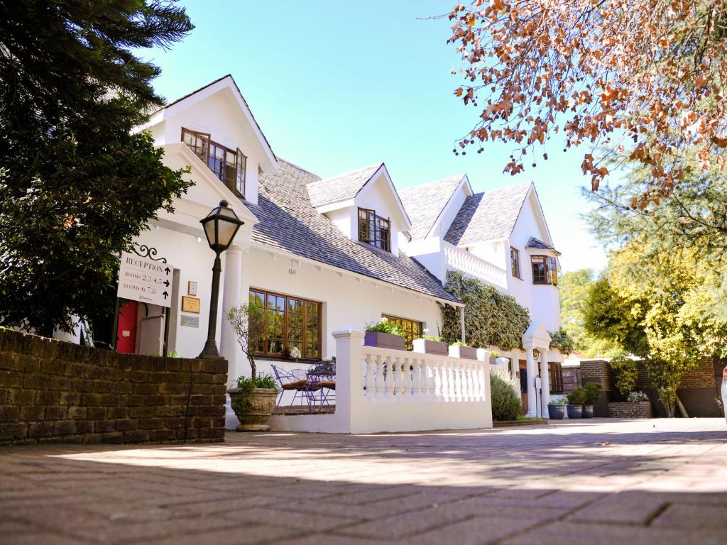 a white house with a fence in front of it at 5th Avenue Gooseberry Guest House in Johannesburg