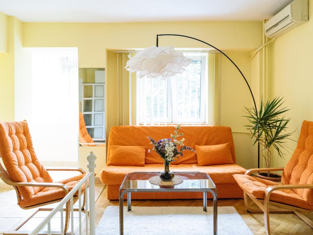 a living room with an orange couch and two chairs at Herastrau Arancia Studio - Business District in Bucharest