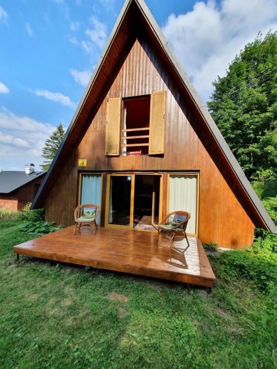 una casa con 2 sillas sentadas en una terraza de madera en Chata pod Tolštejnem, en Jiřetín pod Jedlovou