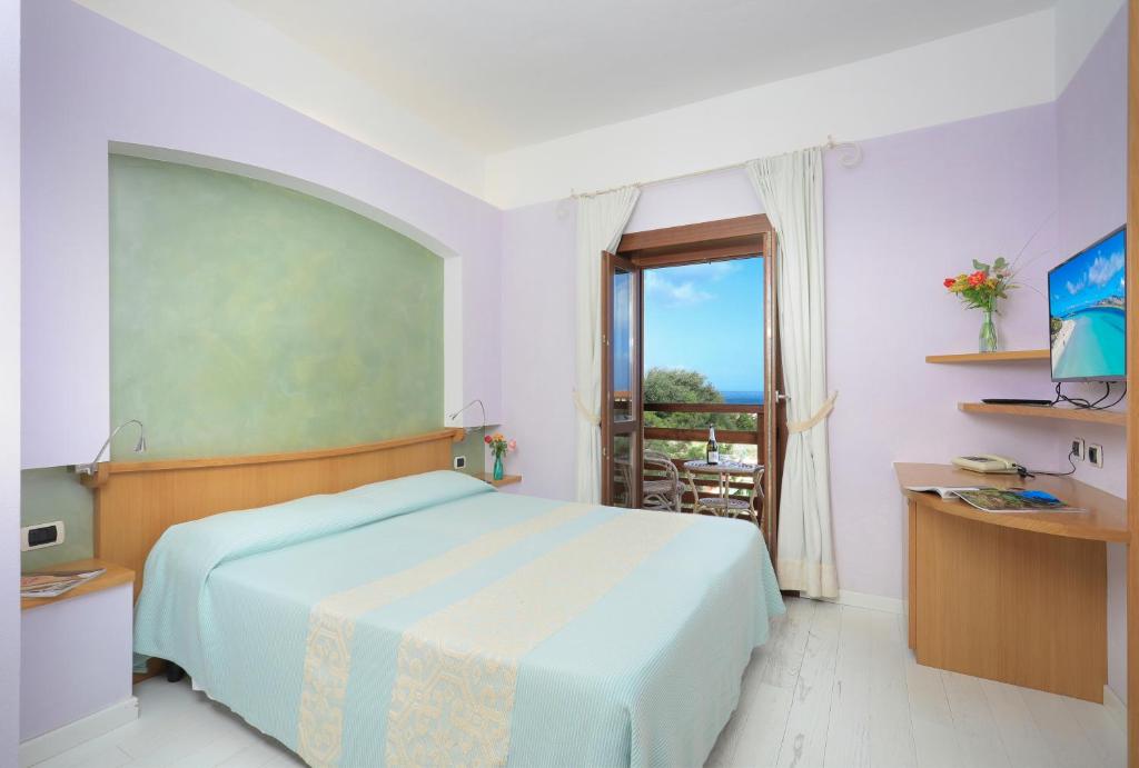 a bedroom with a bed and a desk at Hotel Cala Reale in Stintino