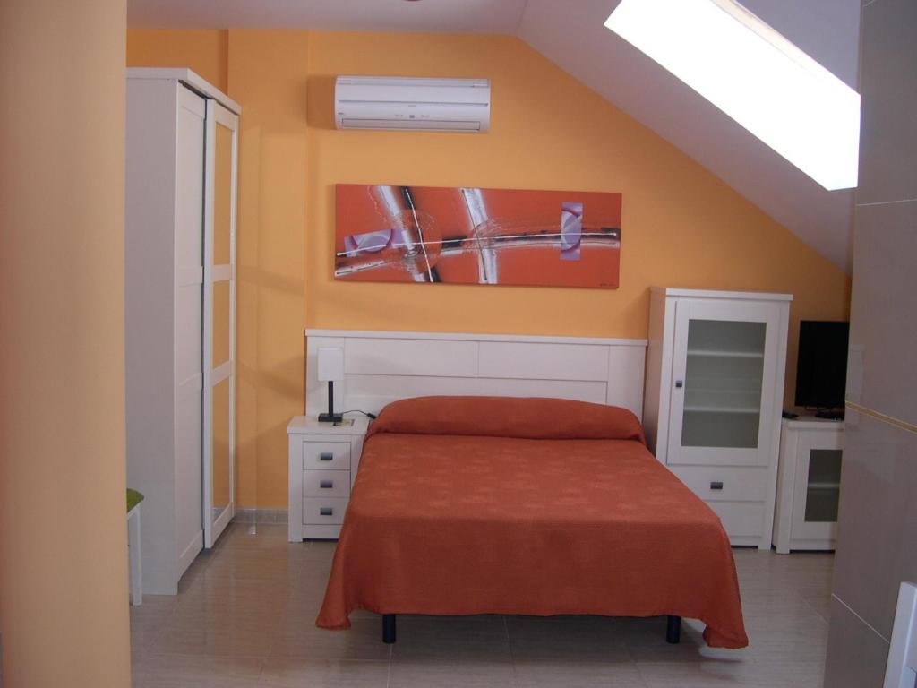 1 dormitorio con 1 cama con pared de color naranja en Apartamentos Turisticos de Hospedaje Don Diego, en Tomelloso