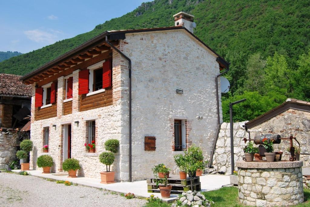 a stone building with red shutters on a mountain at Monte Grappa Guest House in Romano D'Ezzelino
