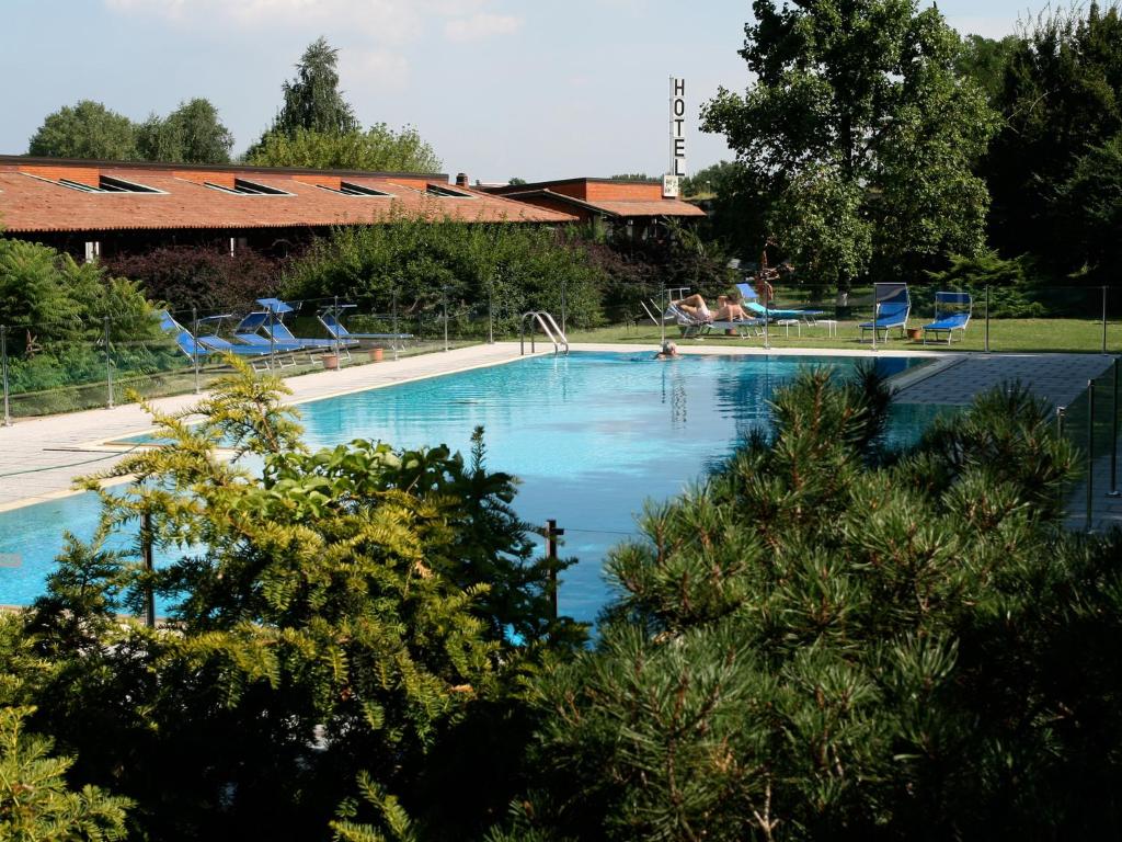 una gran piscina con sillas azules y árboles en Golf Hotel, en Lainate