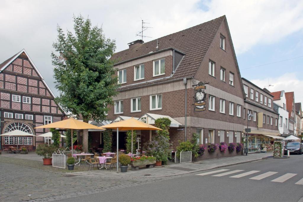 un edificio con tavoli e ombrelloni su una strada cittadina di Hotel Restaurant Vogt a Rietberg
