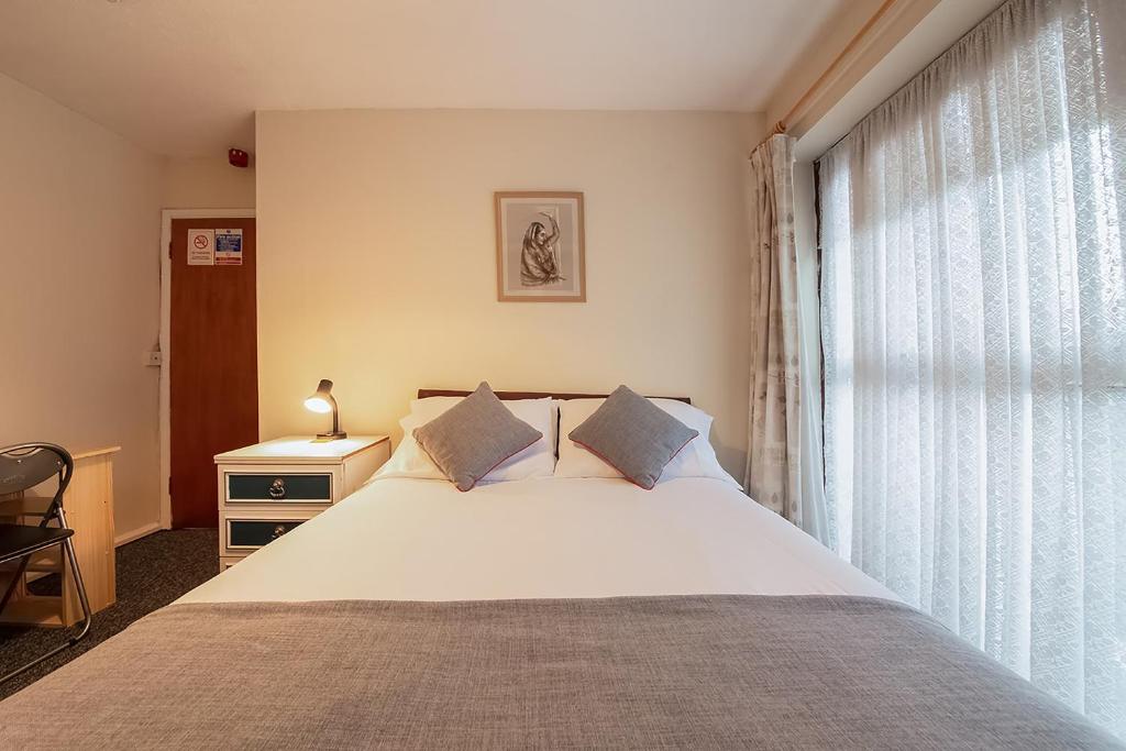 Un dormitorio con una cama grande y una ventana en OYO Honeycroft Lodge, en Uxbridge