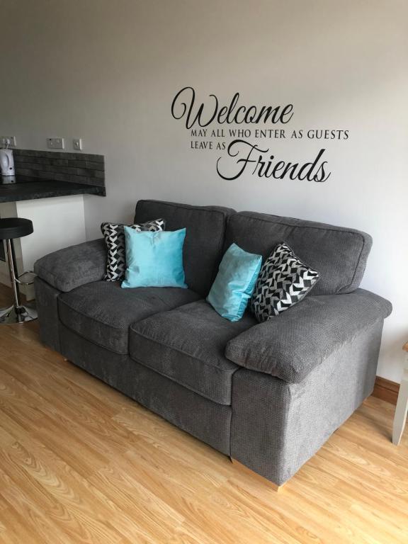 eine Couch in einem Wohnzimmer mit einem Willkommensschild an der Wand in der Unterkunft Our Wendy House in Holsworthy