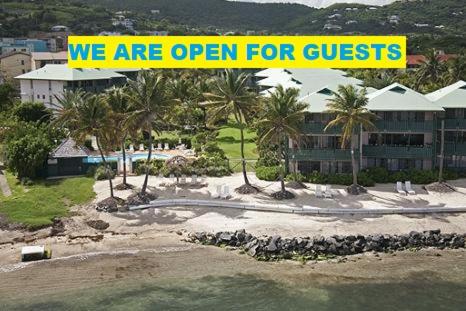 a yellow sign that says we are open for guests at Colony Cove Beach Resort in Christiansted