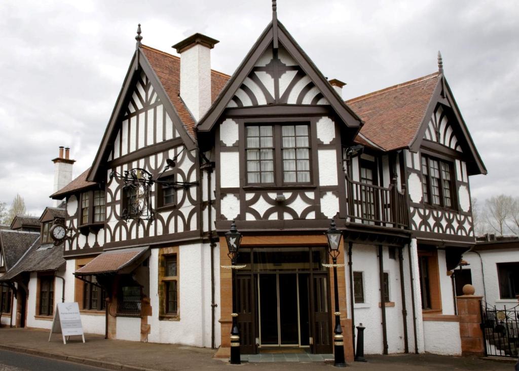 an old black and white building on a street at The Popinjay Hotel in Larkhall