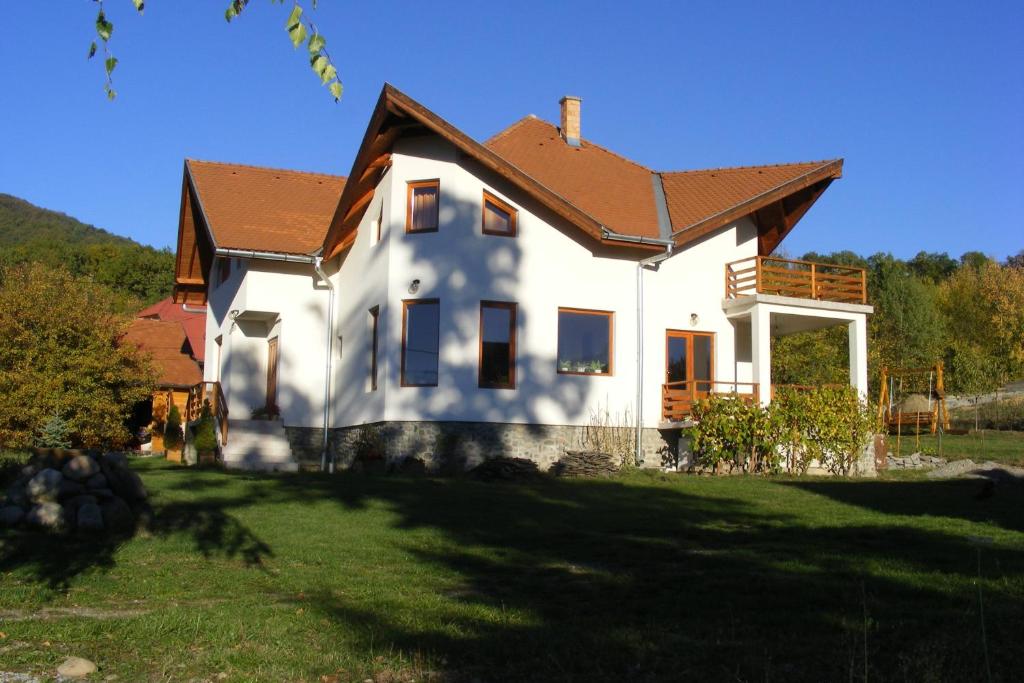 una casa blanca con techo marrón en un patio en Casa Lacul Mierlei, en Sovata