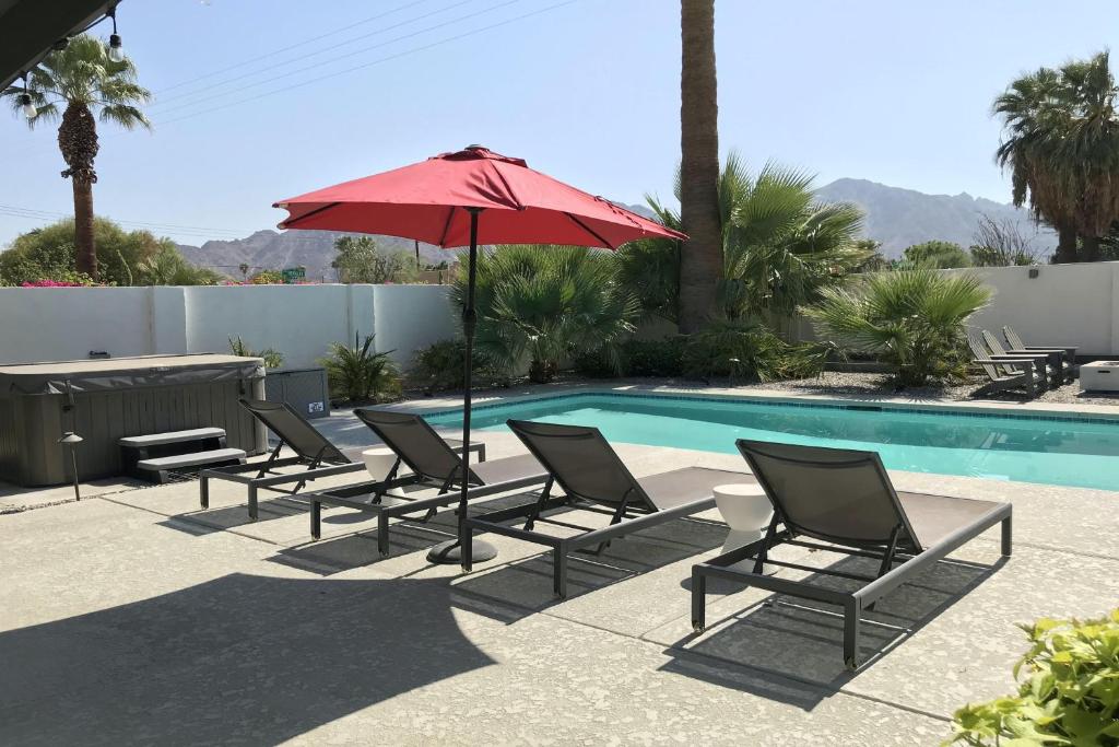 een groep stoelen en een parasol naast een zwembad bij Jewel of the Desert 259-342 in La Quinta