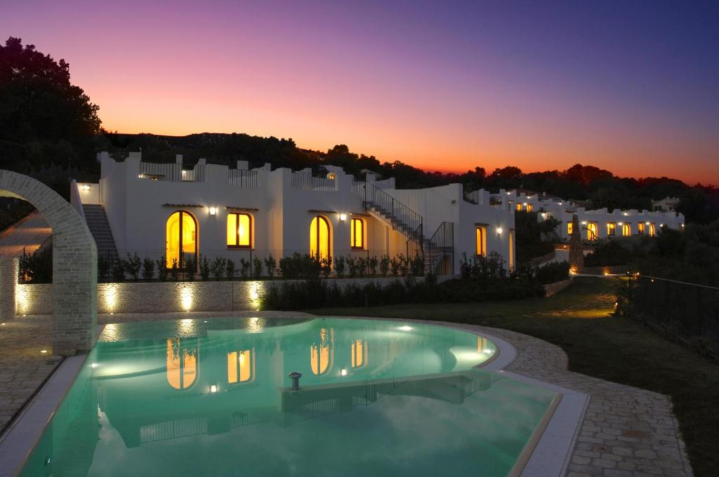 a villa with a swimming pool in front of a building at Baia Delphis Resort in Vasto