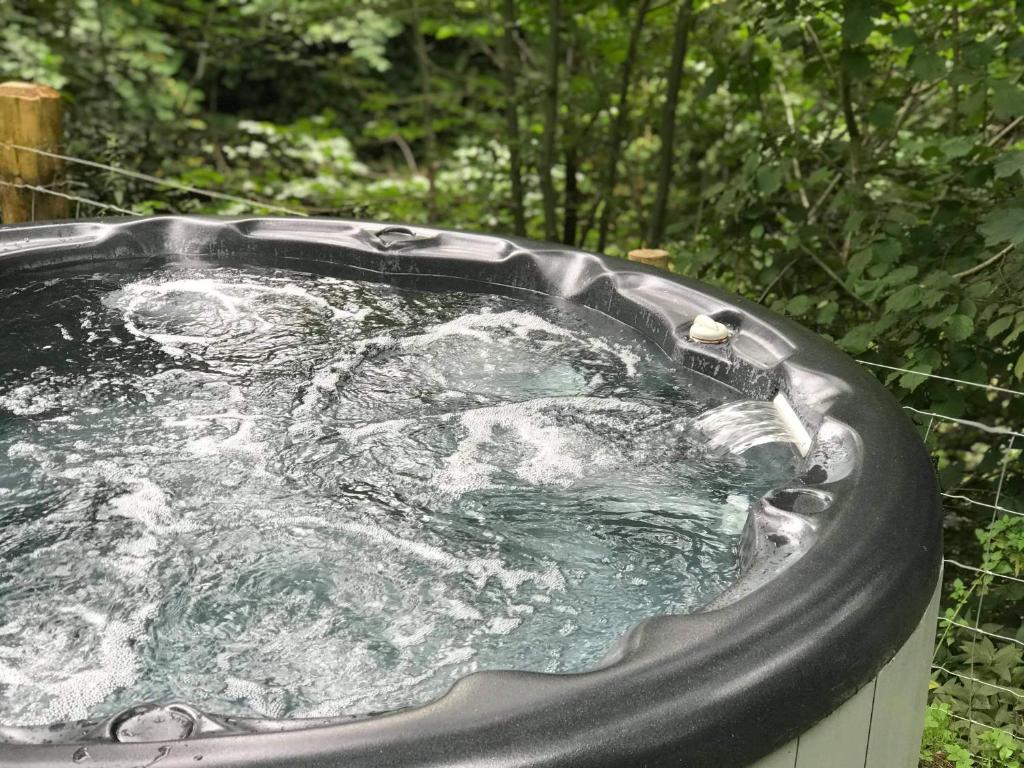a tub filled with water in a garden at Scaurbridge Cottage with Hot Tub and Sauna in Thornhill
