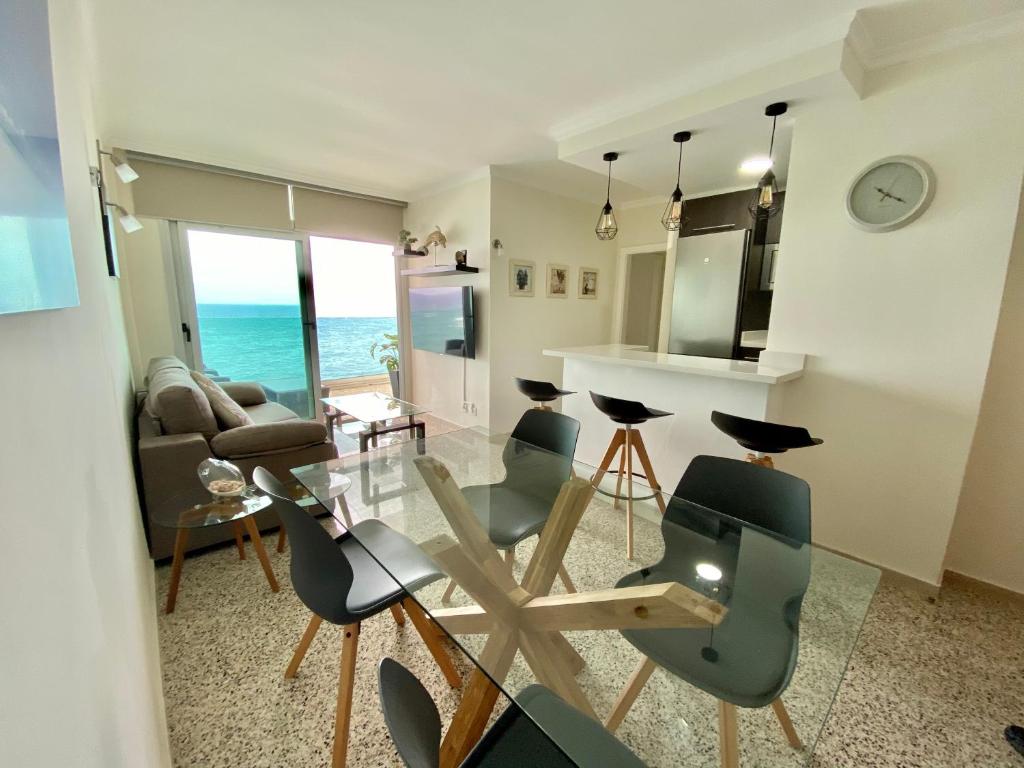 uma sala de estar com uma mesa de vidro e cadeiras em Hermoso edificio Frente al mar con gran terraza y hermosas vistas em Las Palmas de Gran Canaria