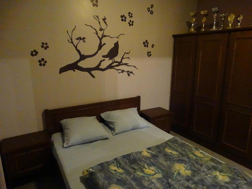 a bedroom with a bed with a branch and birds on the wall at Gîte Le Randonneur in Daverdisse