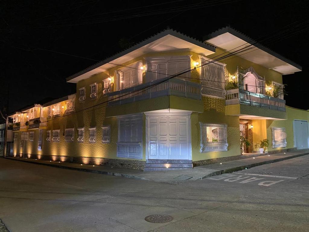 a large yellow building with balconies on a street at night at Casa Hotel Las Orquideas in Circasia