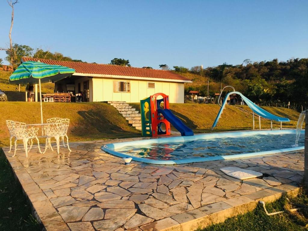 uma pequena piscina com escorrega e um parque infantil em Sítio Santo Agostinho em Porangaba