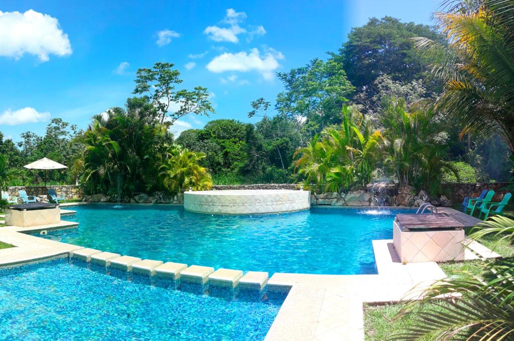 a swimming pool in a resort with trees in the background at Axkan Palenque in Palenque