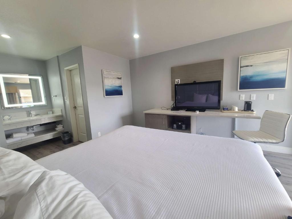 um quarto com uma cama branca e uma televisão em Best Western Orange Plaza em Orange