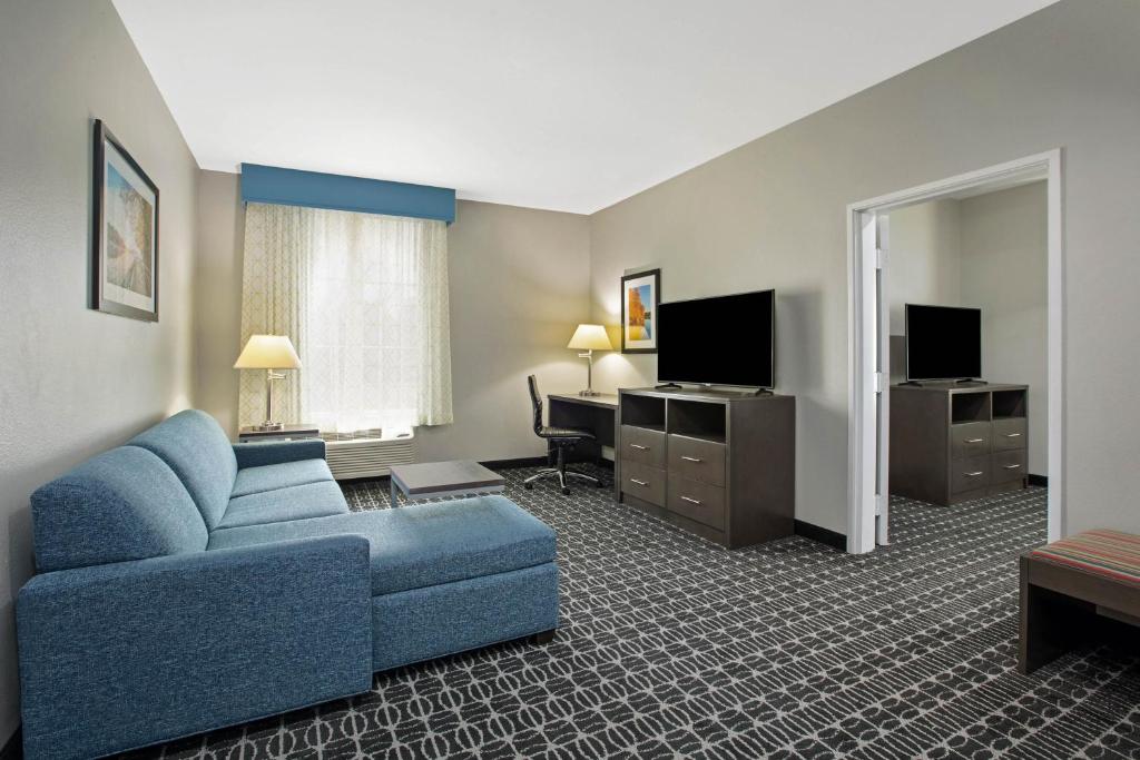 a living room with a blue couch in a hotel room at La Quinta by Wyndham Sulphur Springs in Sulphur Springs