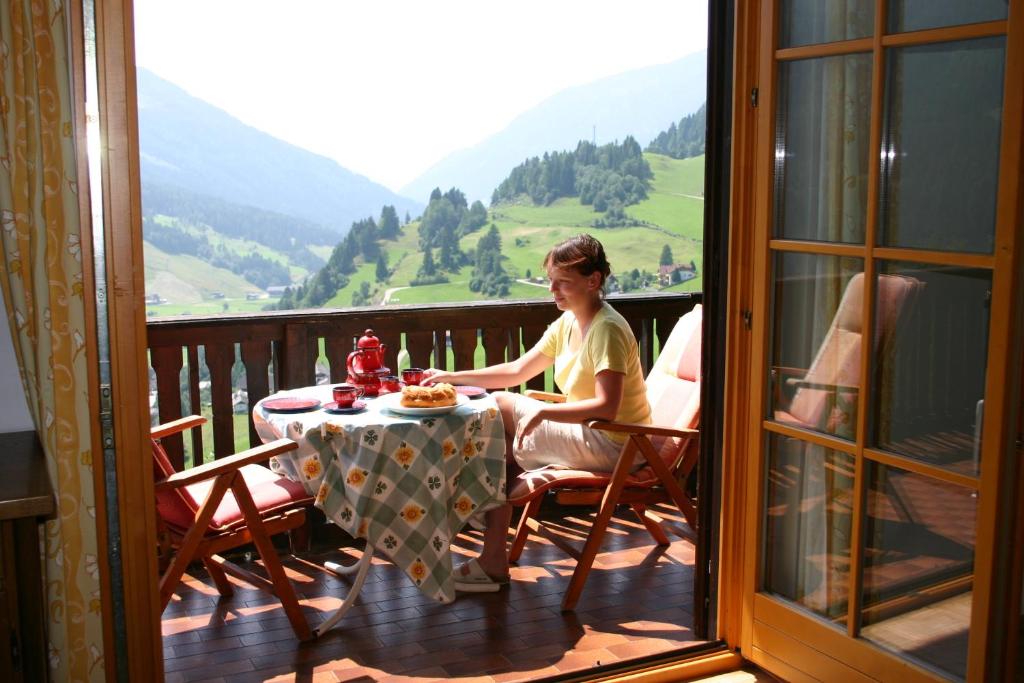 una persona sentada en una mesa en un balcón en Haus Ilse, en Bad Kleinkirchheim