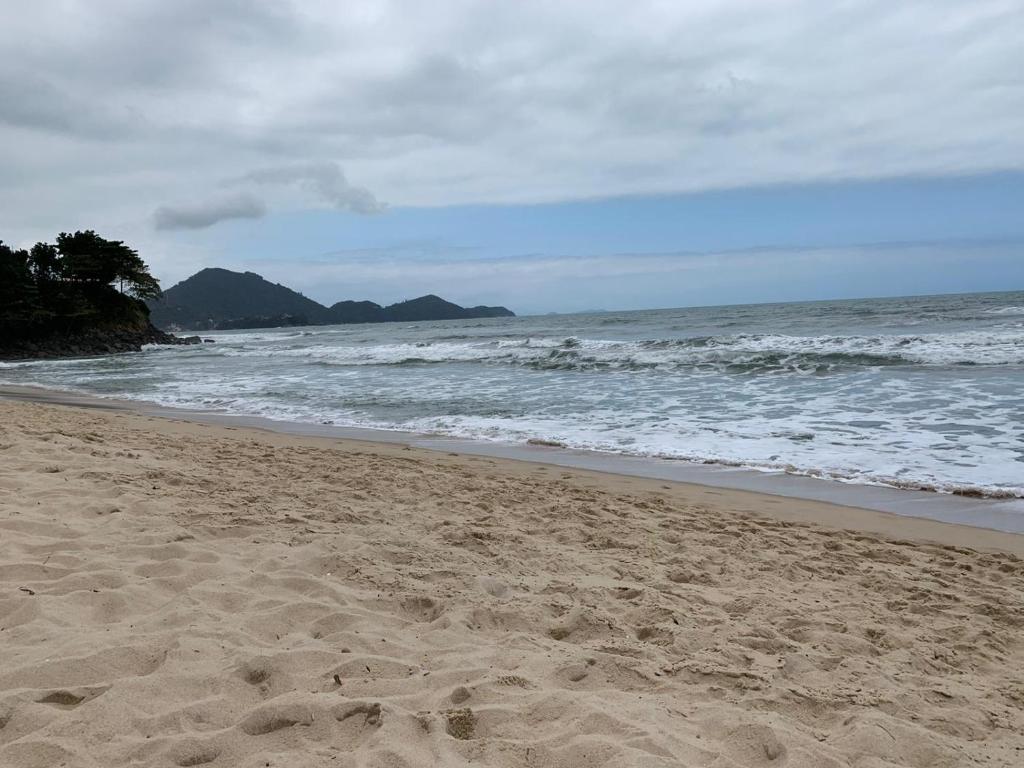 una playa de arena con olas en el océano en Apartamento - Ubatuba - Toninhas - 350 passos da praia - 350 steps to the beach - Costa Verde en Ubatuba