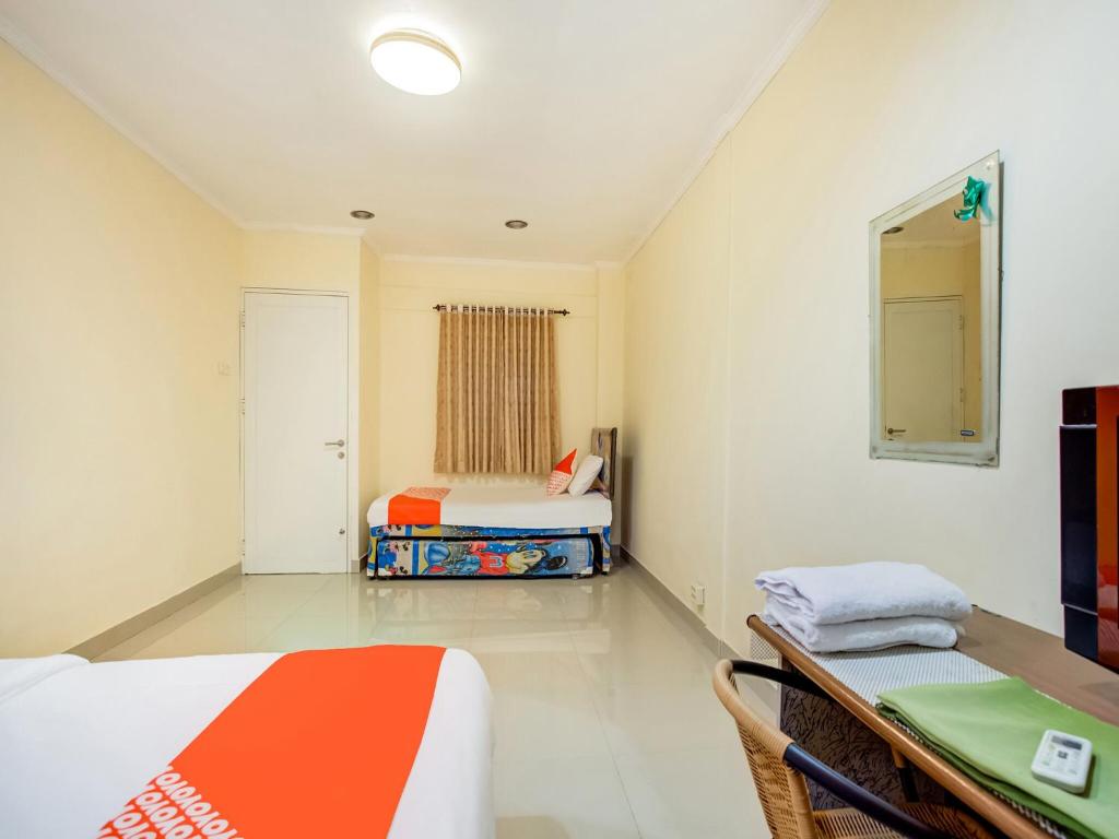 a bedroom with two beds and a table and a mirror at Hotel O Sofia Homestay Syariah in Bogor