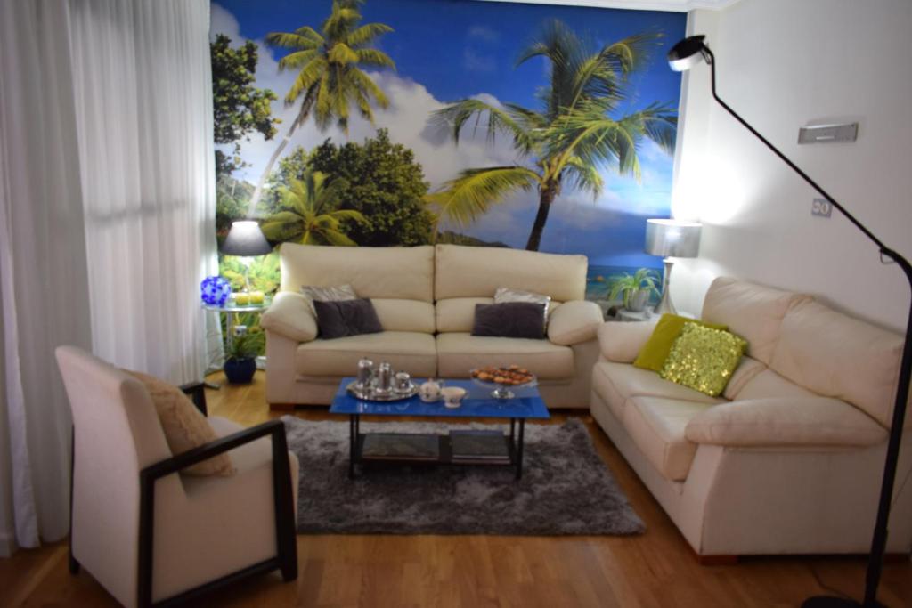 a living room with a white couch and a palm tree mural at Alojamientos Villarias Murcia in Murcia