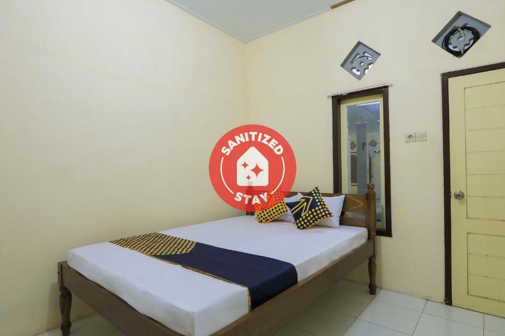 a bedroom with a bed with a red sign on it at OYO 2371 Islami Family Residence in Blimbingsari