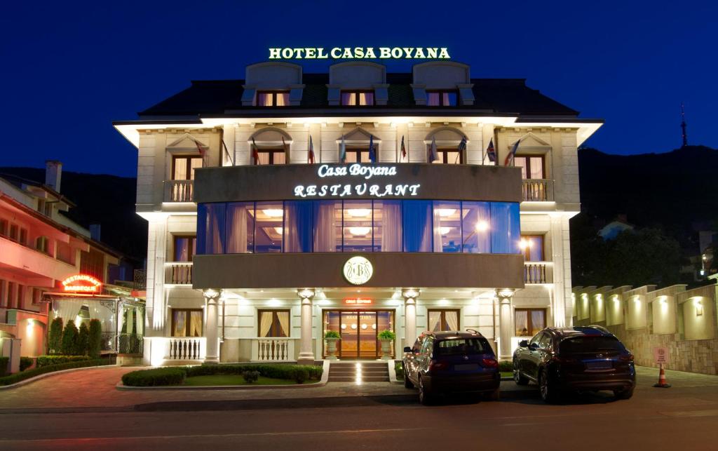 Casa Boyana Boutique Hotel في صوفيا: مبنى فيه سيارات تقف امامه