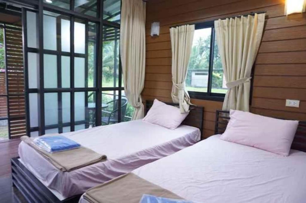 two beds sitting in a room with windows at Baan Rim Nam Resort in Phangnga