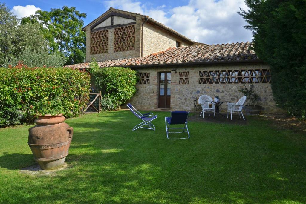 ein Haus mit einem Garten mit Stühlen und einem Tisch in der Unterkunft Betulla A, Betulla B, Betulla C - Happy Rentals in San Gimignano