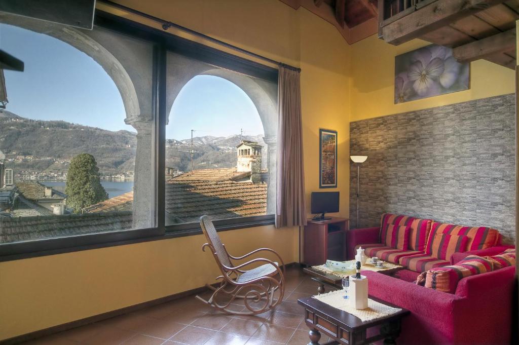 a living room with two red couches and a large window at Appartamenti Orta in Orta San Giulio