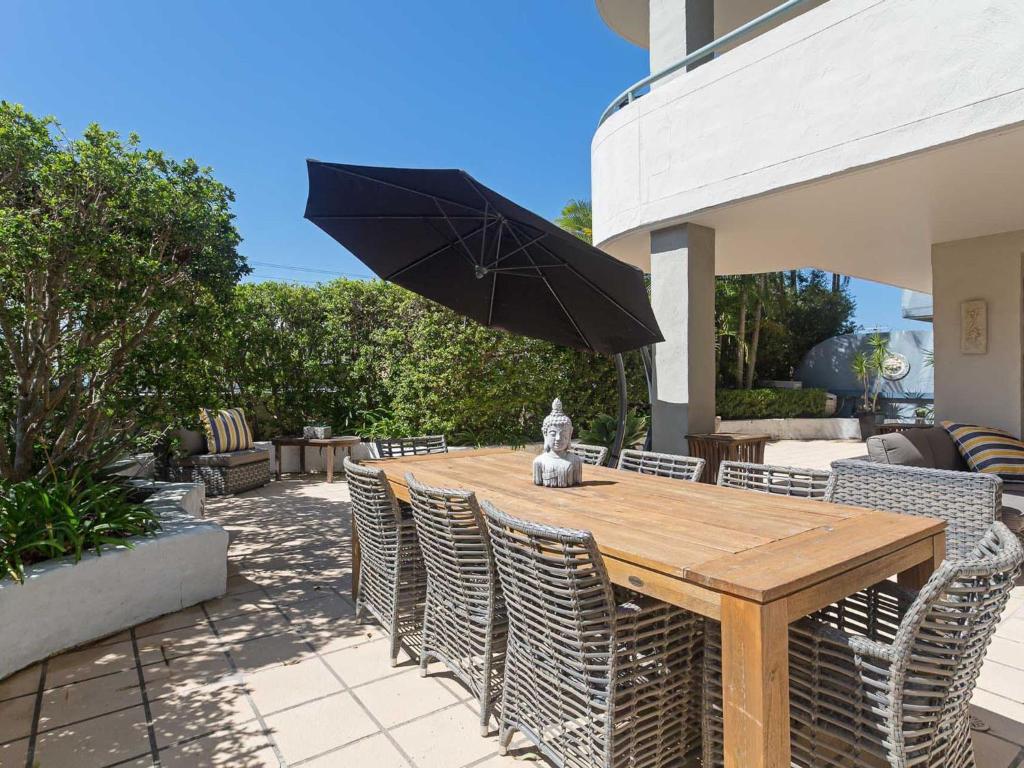 a wooden table with chairs and an umbrella on a patio at Peninsula Waters 1 Aircon pool and massive outdoor area in Soldiers Point