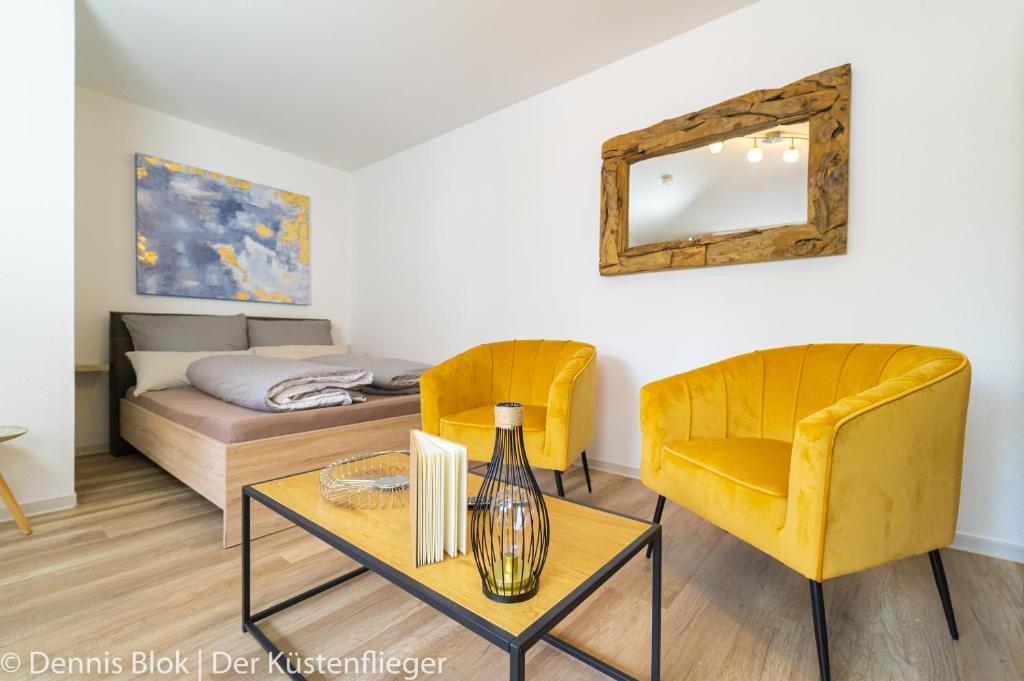 a living room with a yellow chair and a bed at Möwennest 3 in Emden
